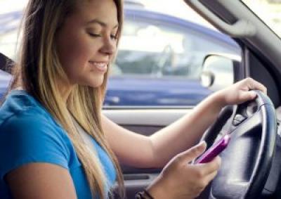 Teenager at the wheel looking at her phone